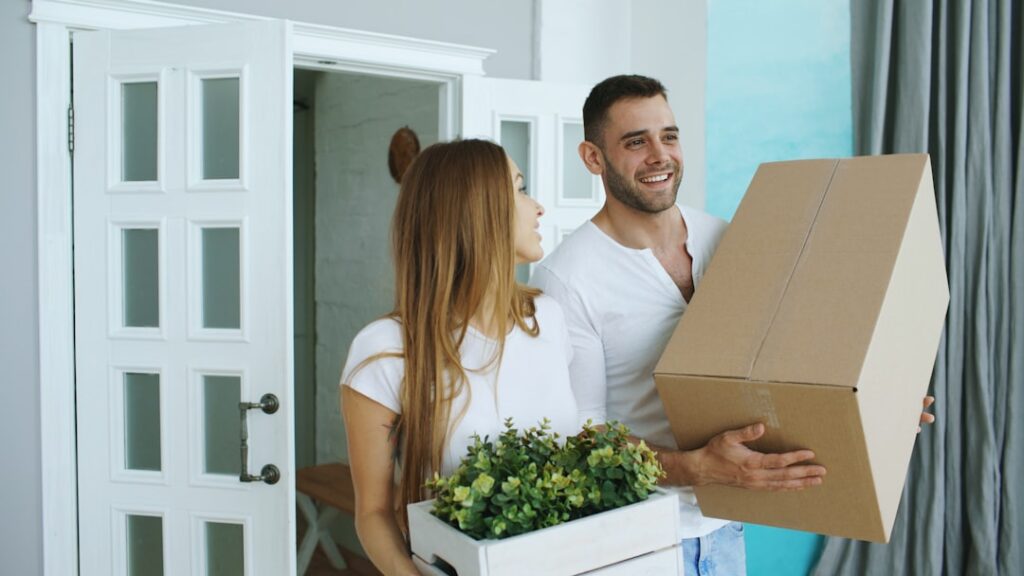 Couple carrying moving boxes and plant
