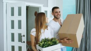 Couple carrying moving boxes and plant